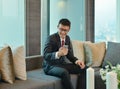 Business Asian man using a smartphone on sofa in luxury condo Royalty Free Stock Photo