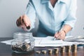 Business asian woman hand put coins in piggy bank on wood table background, saving money wealth and financial concept, finance, Royalty Free Stock Photo