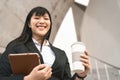 Business Asian woman holding laptop and coffee cup outdoor - Young smiling Chinese girl ready for working Royalty Free Stock Photo