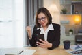 business asian woman wearing glasses and suit cheerful happy smile and working online with mobile smart phone and celebrating at Royalty Free Stock Photo