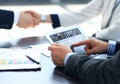 Business associates shaking hands in office, video conferencing with colleagues on digital tablet Royalty Free Stock Photo