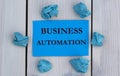 BUSINESS AUTOMATION - word on blue paper on a light background with crumpled pieces of paper