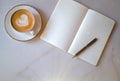 Business background concept. Closeup of white coffee cup in a saucer, notepad, black pen on table with free space. Latte Royalty Free Stock Photo