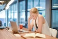 Business blonde girl writing a book and phoning in front of a la Royalty Free Stock Photo