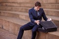Business, briefcase and man sitting on steps outside law firm in city, outdoor commute and sidewalk of court building Royalty Free Stock Photo