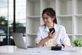 Business Caucasian woman Talking on the phone and using a laptop with a smile while sitting at modern office Royalty Free Stock Photo