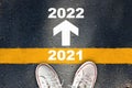 New year 2021 to 2022 and white arrow sign with yellow line marking on asphalt road Royalty Free Stock Photo