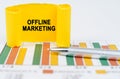 On the business charts are a pen and a paper plate with the inscription - OFFLINE MARKETING