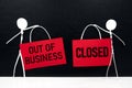 Business closure and bankruptcy concept. Stick man figure holding red we`re closed signage in black background with copy space. Royalty Free Stock Photo