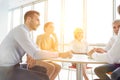 Business colleagues discussing while sitting at table in new office with yellow lens flare in background Royalty Free Stock Photo