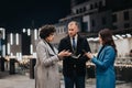 Business colleagues in a discussion outdoors at night with city lights. Royalty Free Stock Photo