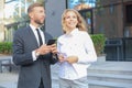 Business colleagues looking at mobile phone standing near office building Royalty Free Stock Photo