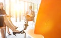 Photo of Business colleagues planning strategy while sitting on chairs during meeting with yellow lens flare in background Royalty Free Stock Photo