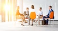 Photo of Business colleagues planning strategy while sitting on chairs during meeting With yellow lens flare in background Royalty Free Stock Photo