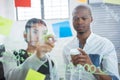 Business colleagues reading sticky notes on glass Royalty Free Stock Photo