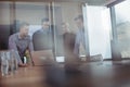 Business colleagues seen through glass discussing around desk during meeting Royalty Free Stock Photo