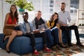 Business colleagues using electronic devices while sitting on sofa Royalty Free Stock Photo