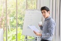 Business and Comminication Concept. Asian young businessman standing looking to camera with holding a white cup of hot coffee and Royalty Free Stock Photo