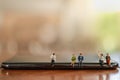 Business and Communication Cencept. Close up of group of businessman and woman miniature figure people sitting on smart mobile