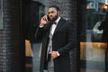 Business communications. Happy young African man in formal wear talking on the mobile phone and smiling while standing outdoors Royalty Free Stock Photo