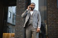 Business communications. Happy young African man in formal wear talking on the mobile phone and smiling while standing outdoors Royalty Free Stock Photo