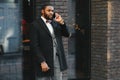 Business communications. Happy young African man in formal wear talking on the mobile phone and smiling while standing outdoors Royalty Free Stock Photo