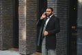 Business communications. Happy young African man in formal wear talking on the mobile phone and smiling while standing outdoors Royalty Free Stock Photo