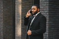 Business communications. Happy young African man in formal wear talking on the mobile phone and smiling while standing outdoors Royalty Free Stock Photo