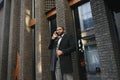 Business communications. Happy young African man in formal wear talking on the mobile phone and smiling while standing outdoors Royalty Free Stock Photo