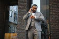 Business communications. Happy young African man in formal wear talking on the mobile phone and smiling while standing outdoors Royalty Free Stock Photo