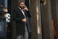 Business communications. Happy young African man in formal wear talking on the mobile phone and smiling while standing outdoors Royalty Free Stock Photo