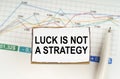 Against the background of business graphics and pens, a sign with the inscription - Luck is Not a Strategy Royalty Free Stock Photo