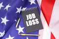 On the American flag lies a pen and a notebook with the inscription - job loss Royalty Free Stock Photo