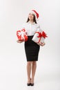 Business Concept - Beautiful young caucasian business woman with santa hat holding gift boxes with copy space on side Royalty Free Stock Photo