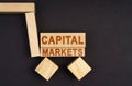 On a black surface, a cart made of blocks and cubes with the inscription - CAPITAL MARKETS