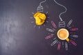 Business concept of brainstorming, idea or start up with light bulb sketch, coffee cup and crumpled paper over chalkboard Royalty Free Stock Photo