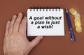 On a brown surface are coins, a pen and a notepad with the inscription -a goal without a plan is just a wish Royalty Free Stock Photo