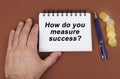 On a brown surface are coins, a pen and a notepad with the inscription - how do you measure success Royalty Free Stock Photo