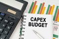 On business charts there is a calculator, a pen and a notepad with the inscription - CAPEX BUDGET