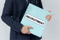 A businessman holds a folder with documents, the text on the folder is - RECRUITMENT