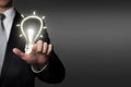 Business idea concept - businessman presses virtual touchscreen interface button - glowing light bulb