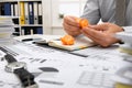 Business concept - businessman working in office and peels a tangerine, table and workspace close view, checks financial reports,