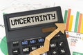 On the business charts there is a calculator on the screen with the inscription - Uncertainty Royalty Free Stock Photo