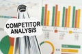 On the business charts there is a notebook on which there is a paper plate with the inscription - Competitor Analysis Royalty Free Stock Photo