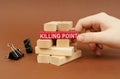 Clamps and wooden blocks lie on a brown surface, a person takes out a red block with the inscription - KILLING POINT