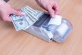 Close-up of a woman& x27;s hand holding several hundred dollar bills above the cash register and tearing off a blank check Royalty Free Stock Photo