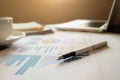 Business concept with copy space. Office desk table with pen focus and analysis chart, computer, notebook, cup of coffee on desk.