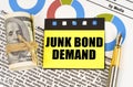 On documents with diagrams there are dollars, a pen and yellow stickers with the inscription - JUNK BOND DEMAND