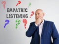 Business concept about EMPATHIC LISTENING question marks with inscription on the gray wall