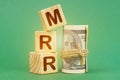 On a green surface, dollars and cubes with the inscription - MRR